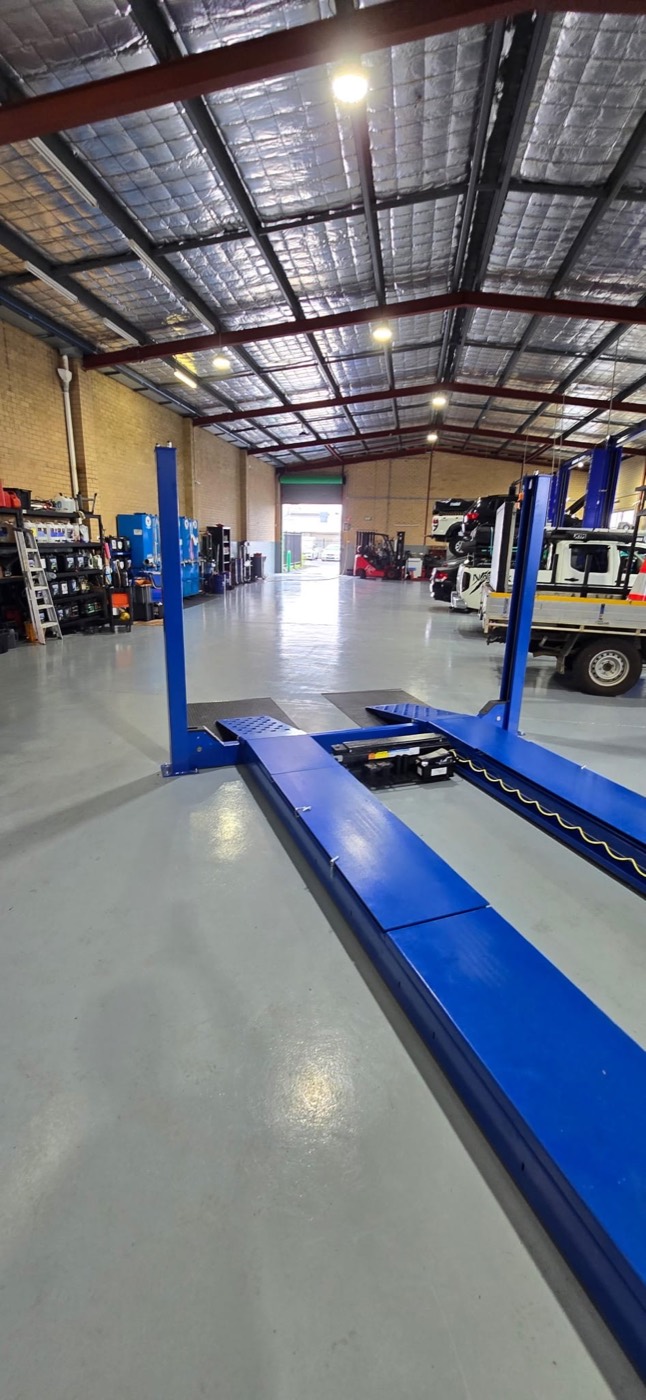 Industrial epoxy floor in a mechanical workshop with car hoists